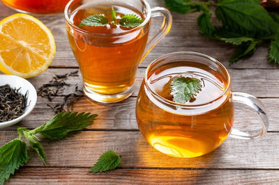 Cup of herbal tea with lemon and fresh mint leaves on a wooden table
