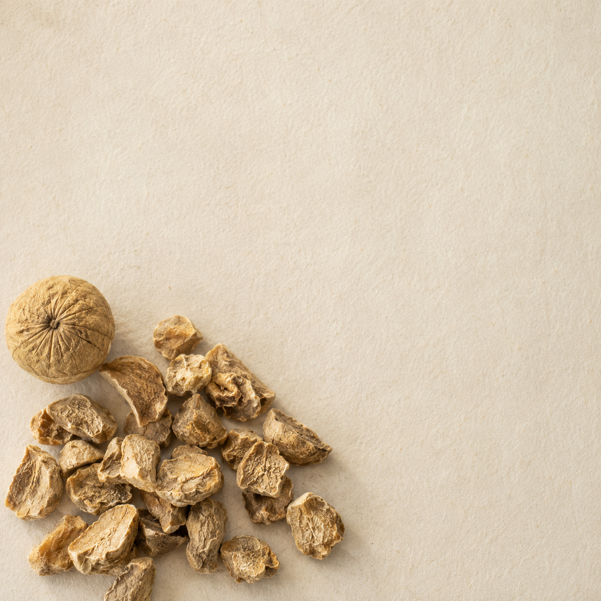 Dried amla pieces and one whole dried Indian gooseberry on pale handmade paper