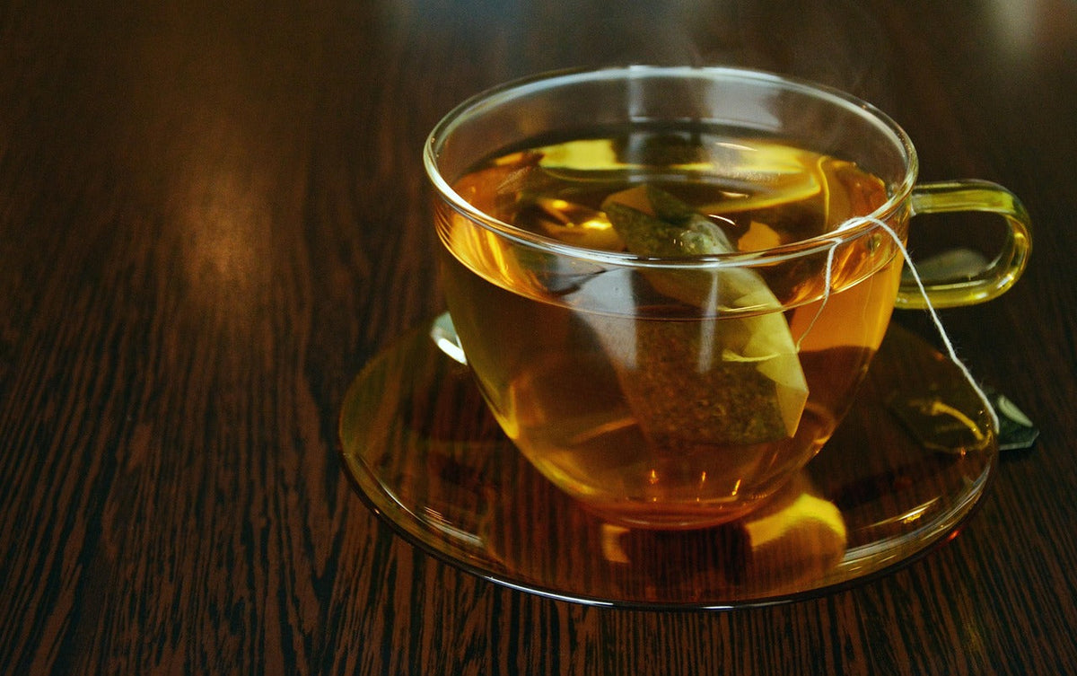 A glass cup of herbal tea on a wooden table